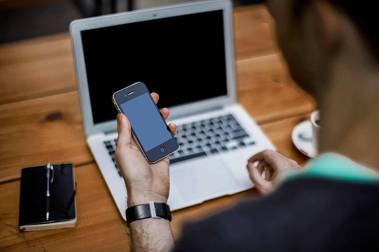 A person working with a laptop and smartphone